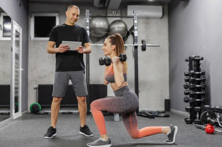 Male trainer training female client on dumbbell back lunge workout
