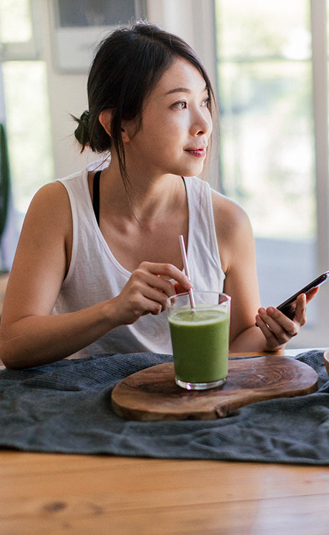 a woman at a table drinking a smoothie for a lower bmi