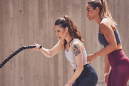 Female trainer with female client using battle rope