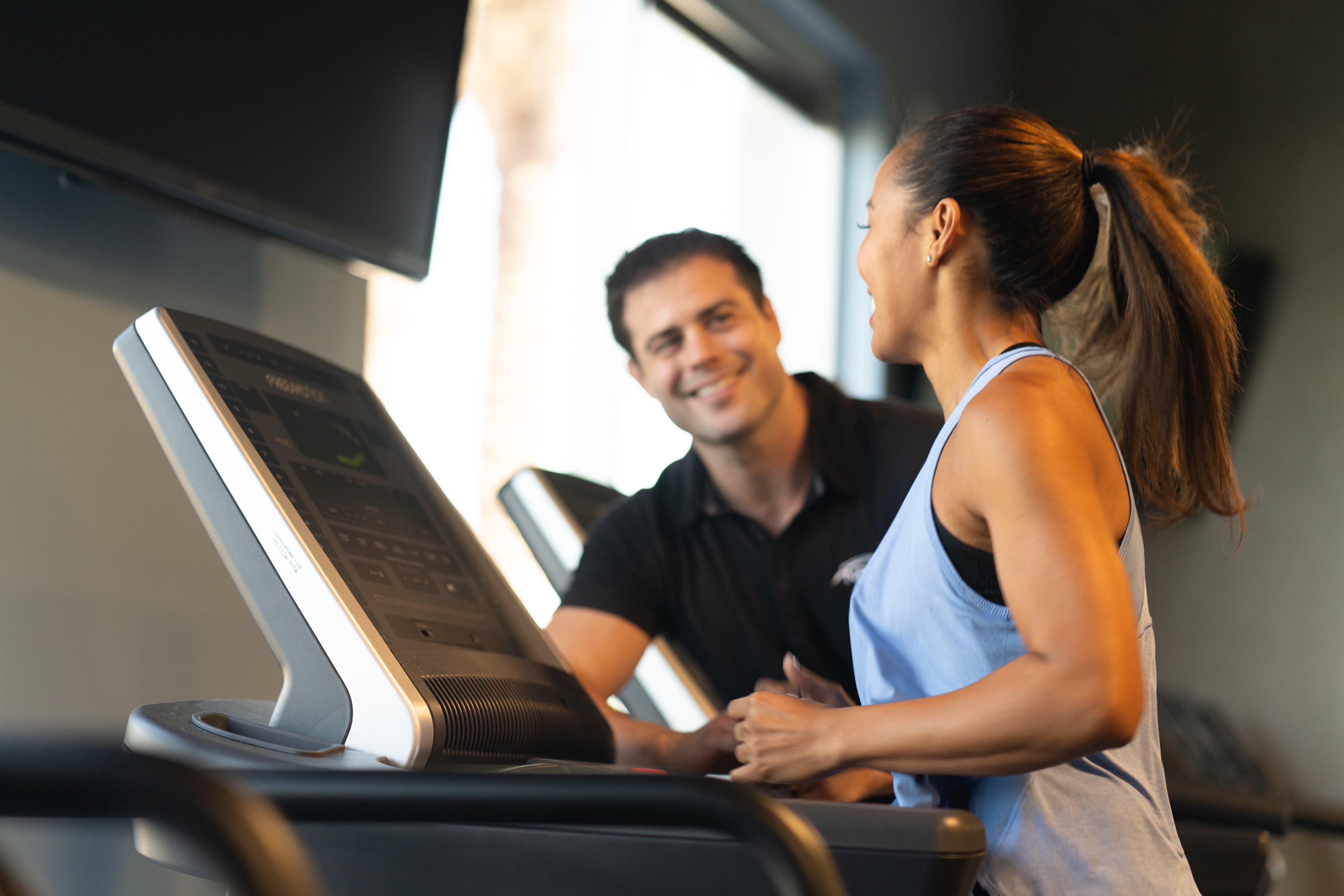 A personal trainer assists a woman using a tablet