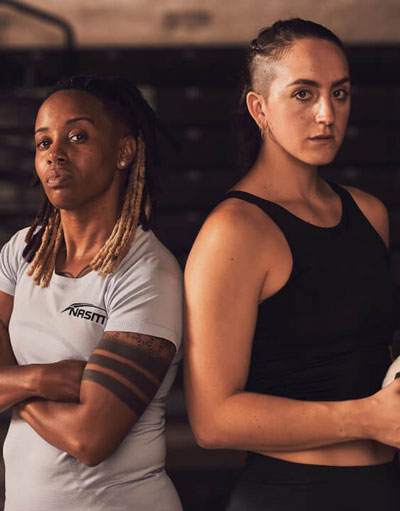 Female NASM trainer standing next to female client inside gymnasium