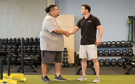 personal trainer and client shaking hands in gym