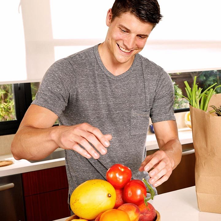Male unpacking produce from paper grocery bag